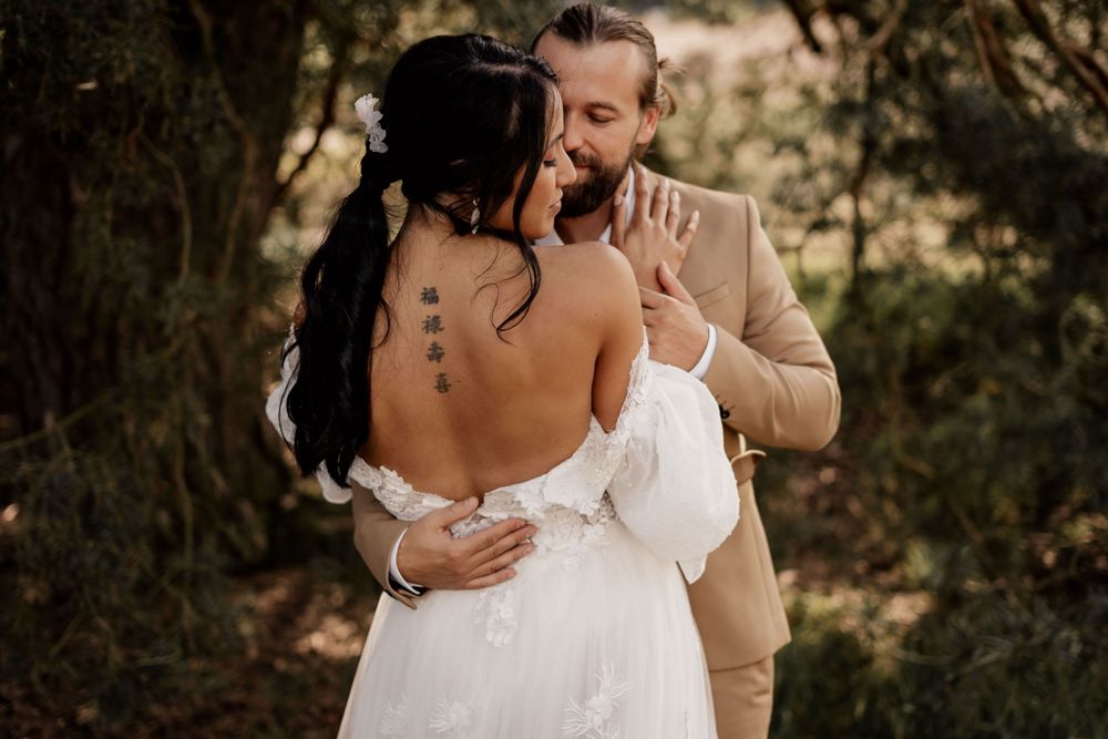 A romantic wedding portrait showing intricate dress details and tender embrace in golden light.