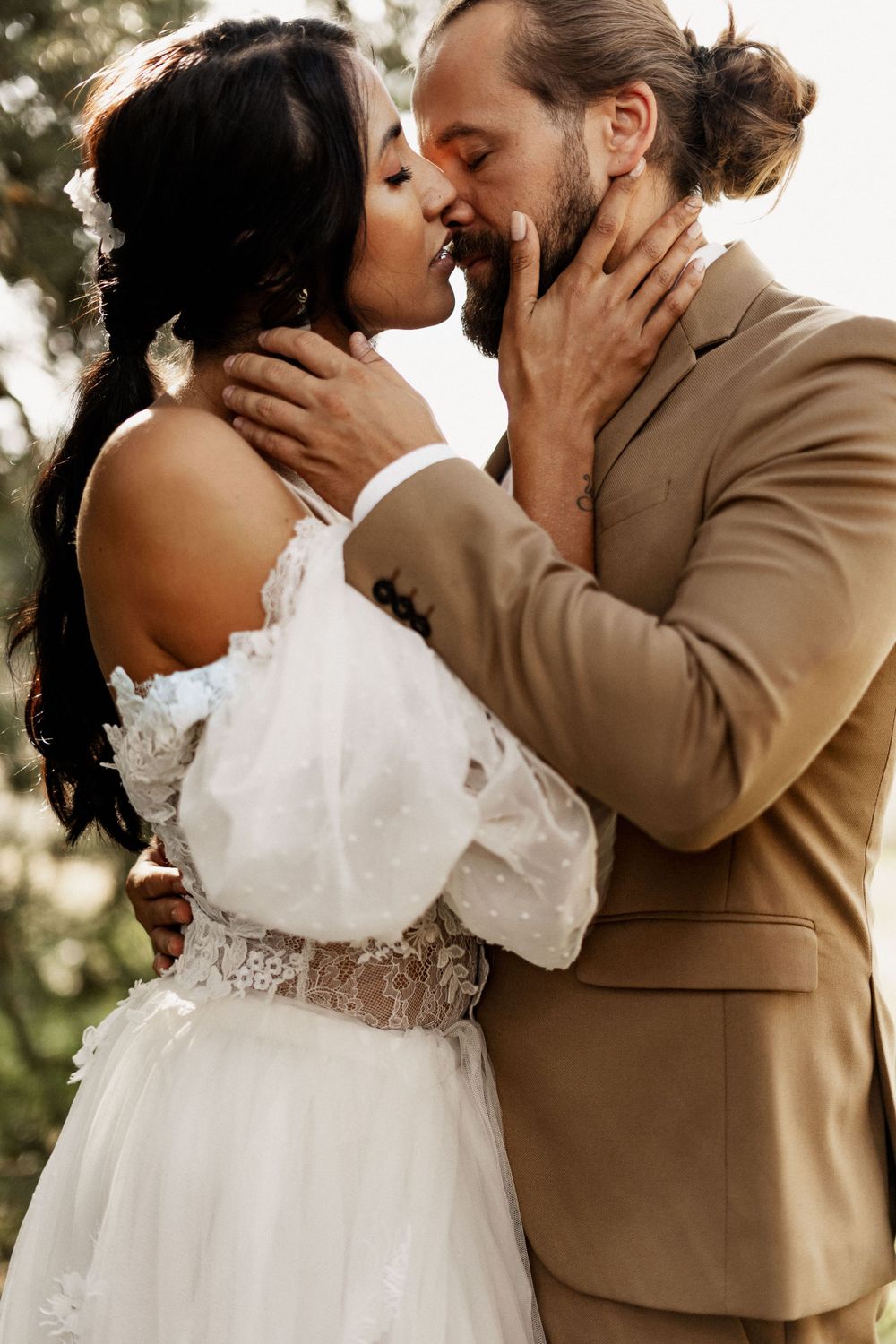Romantic wedding portrait showing tender kiss between newlyweds in natural outdoor setting.