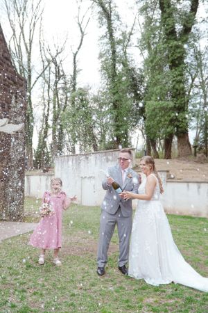 A wedding celebration outdoors with confetti falling while wearing formal attire in a beautiful natural setting.