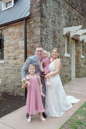 A family group poses together outside a stone building during a formal occasion.