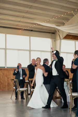 Newlyweds celebrate during their first dance in rustic venue with string lights.