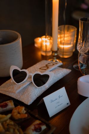 Heart-shaped sunglasses and candlelight create romantic wedding reception table setting.