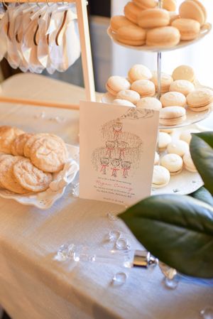 Elegant display of French macarons on tiered stands with decorative cards and magnolia leaves.