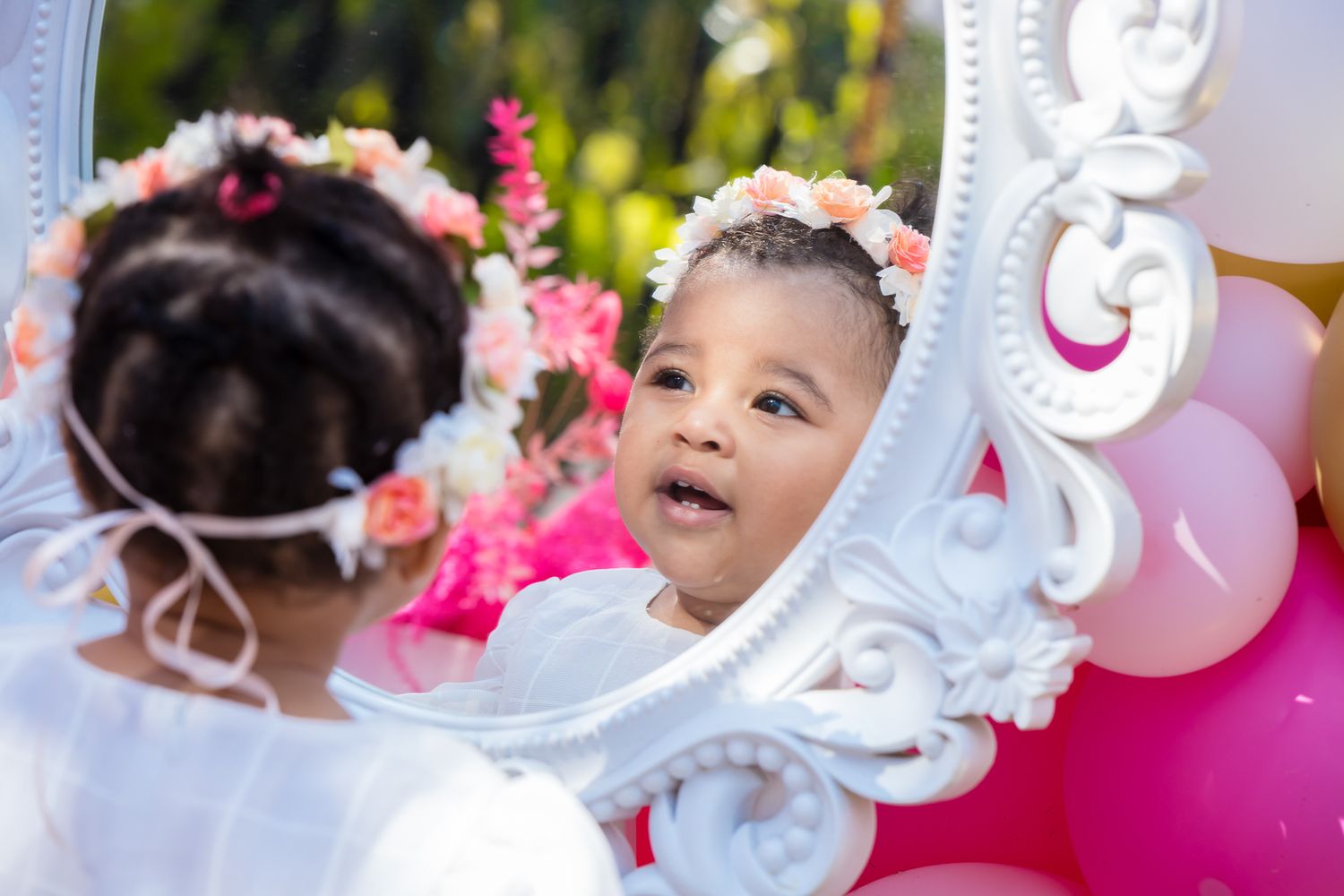 A baby girl looks at her reflection on a beautiful mirror.
