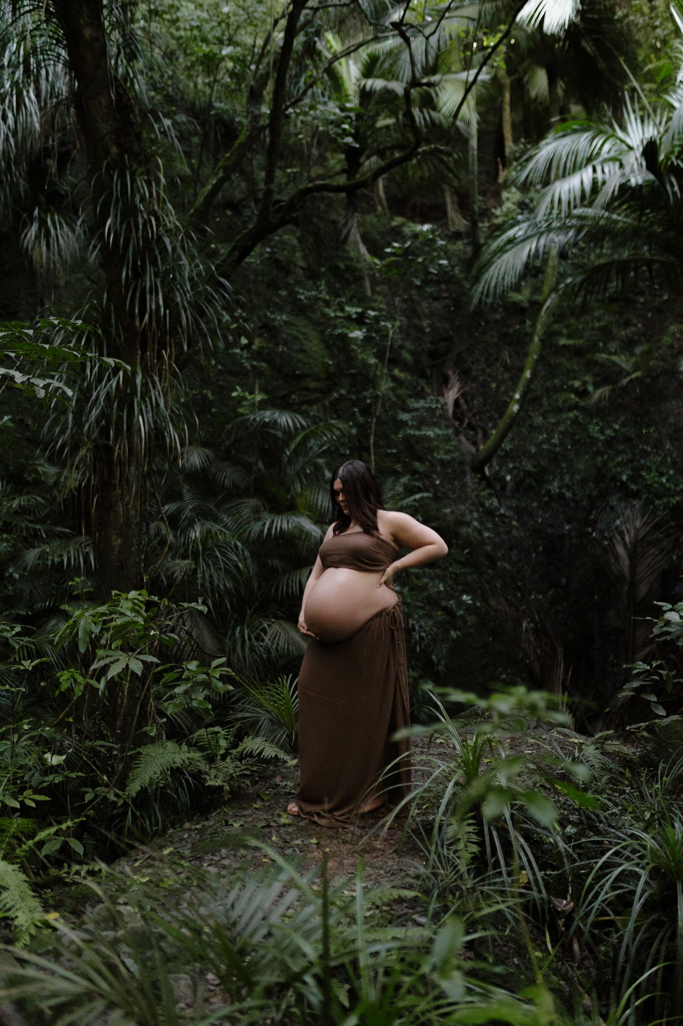 A series of images showing a person in a brown dress walking through a lush tropical forest with palm trees and greenery.