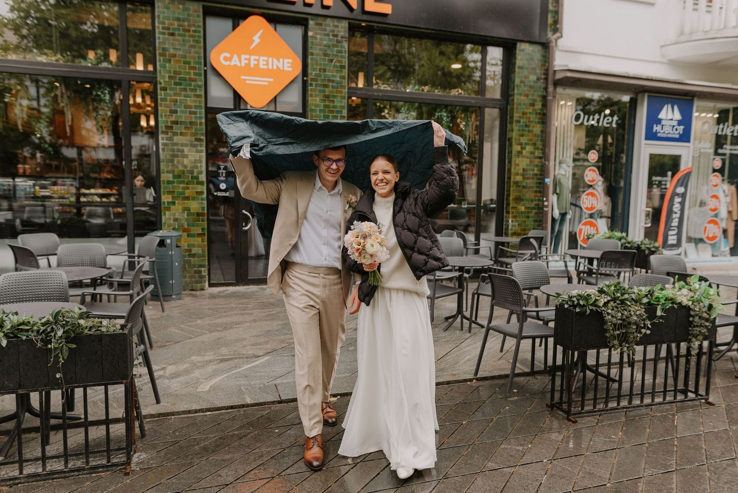 Stylish newlyweds walking together on a city street past storefronts and cafes.