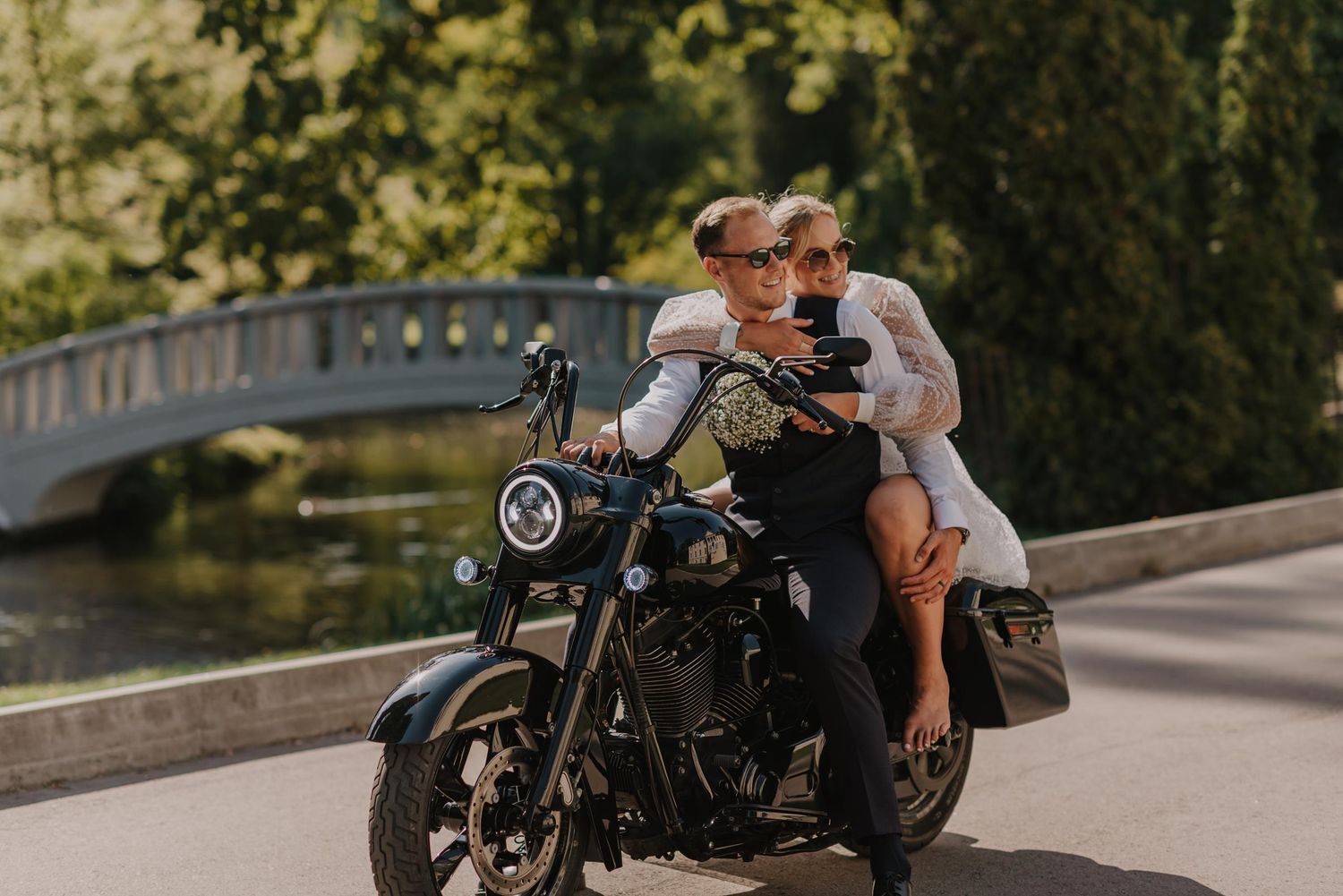 Black motorcycle parked on road with couple enjoying scenic view.