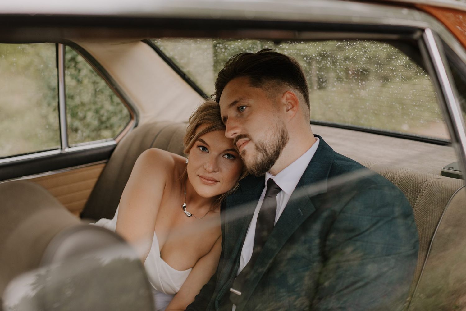 Newlyweds share a tender moment together in a vintage car.