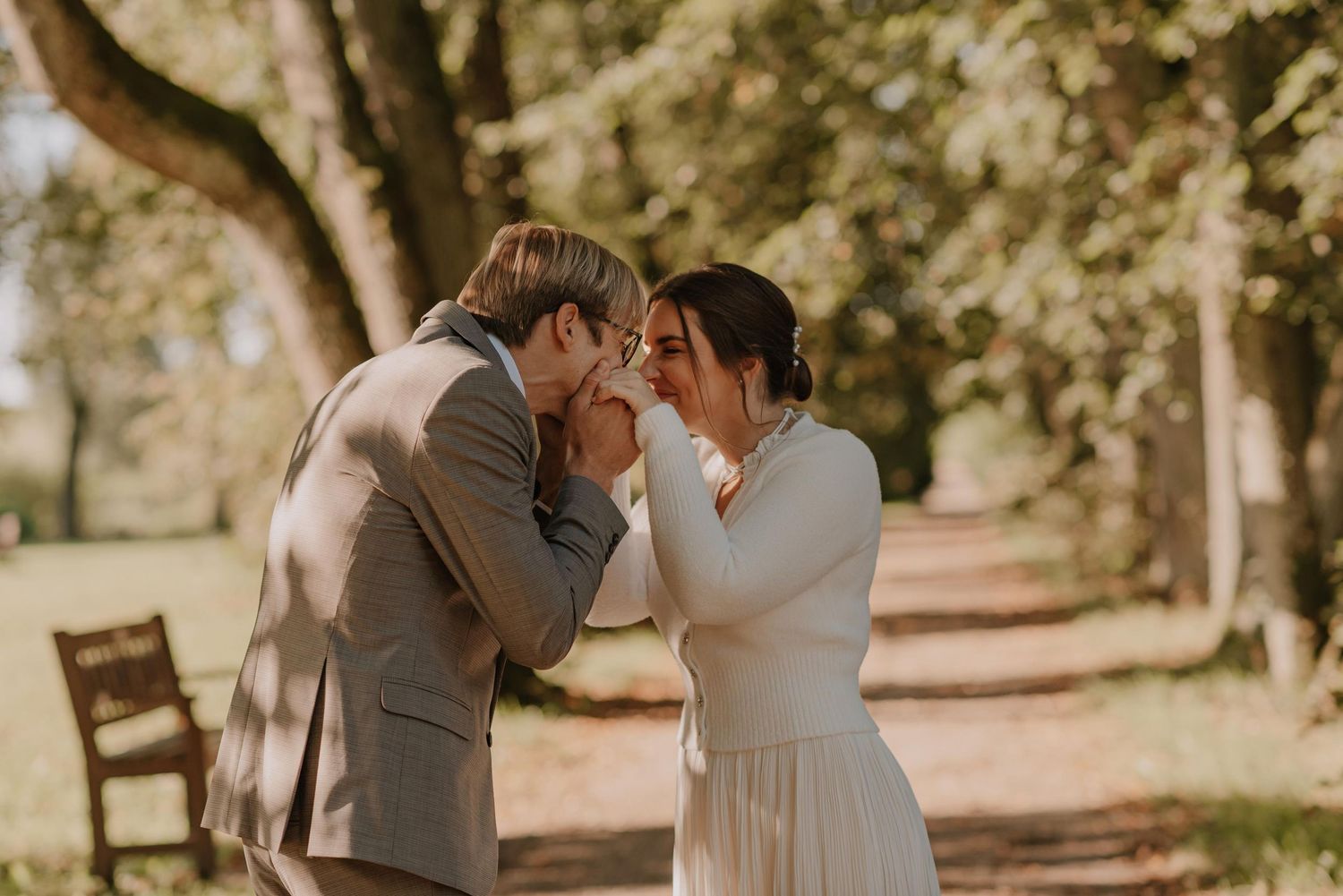 An intimate wedding moment unfolds in a sun-drenched garden setting.