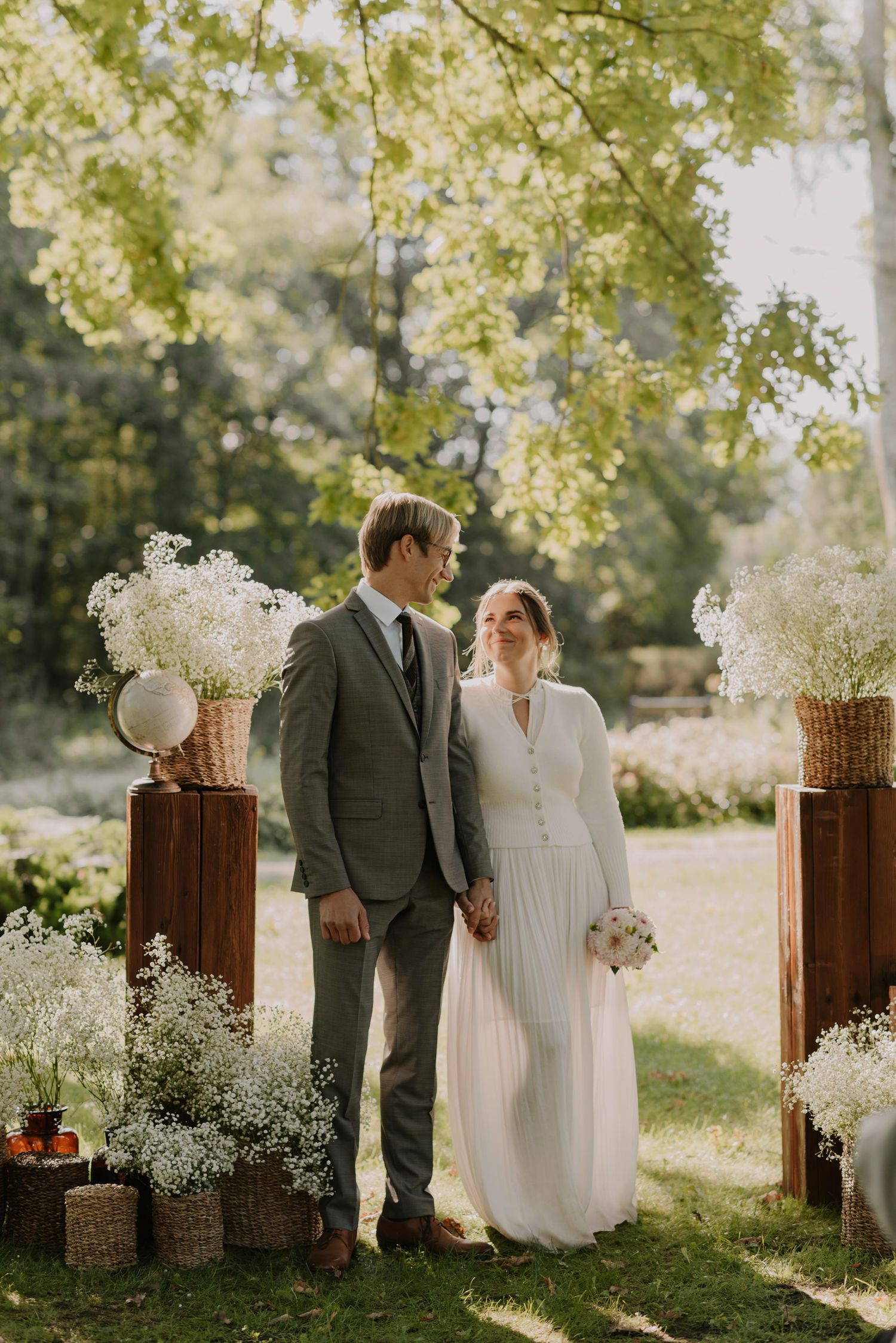 A wedding ceremony setup features rustic wooden posts adorned with delicate baby's breath flowers.