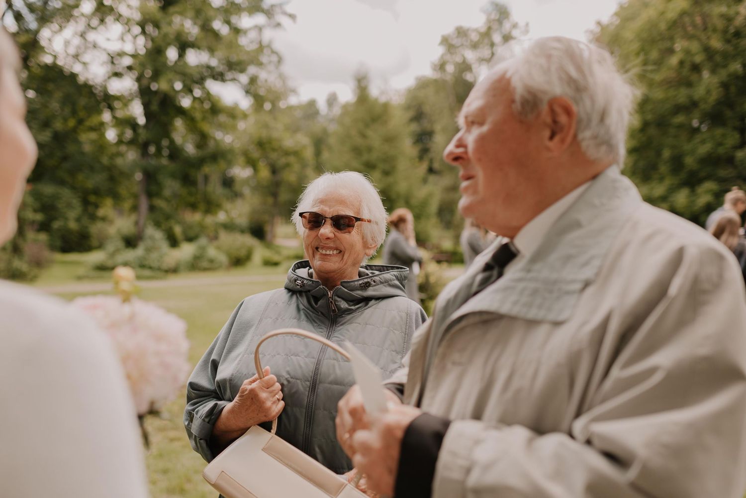 Elderly guests at an outdoor wedding celebration engaging in joyful conversation.