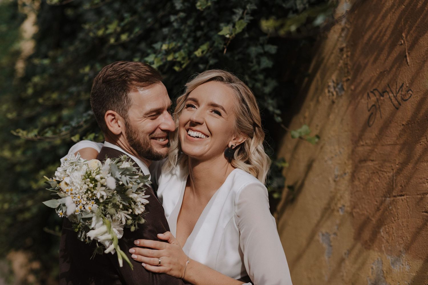 A romantic wedding photography session captured in a natural outdoor setting with soft lighting and white floral bouquet.