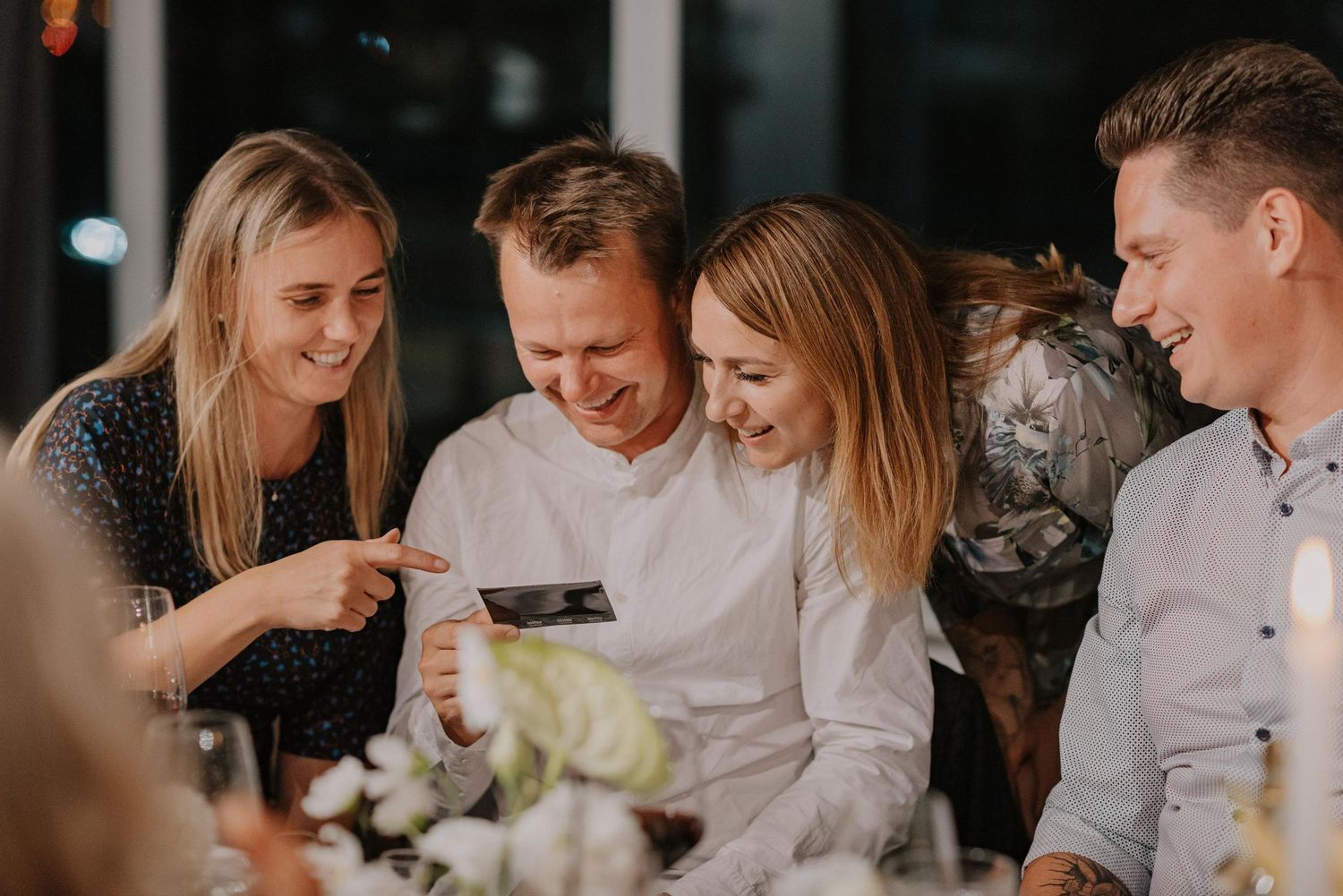 Candid moment of friends laughing and enjoying conversation at a wedding reception.