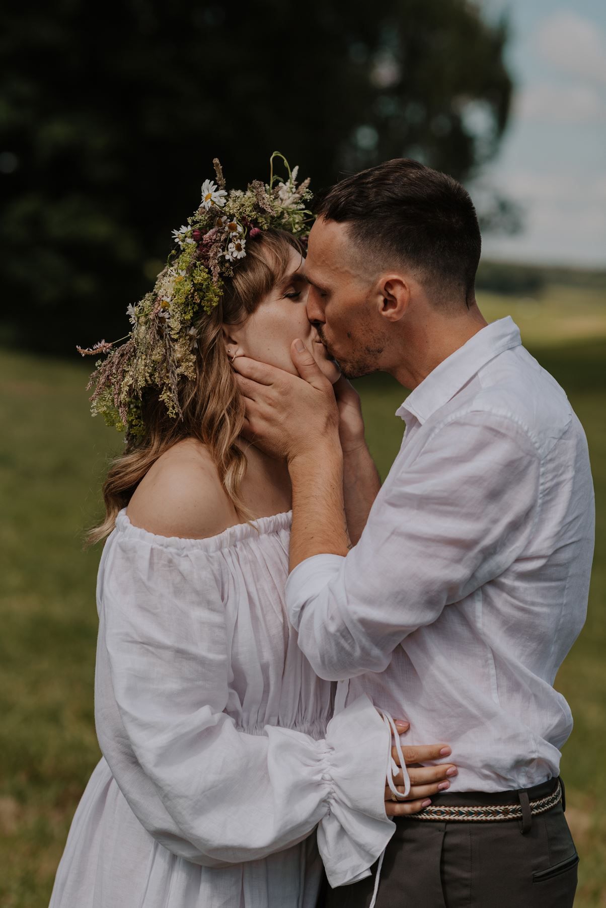 A tender moment captured in a sun-drenched field with wildflowers and natural elements.