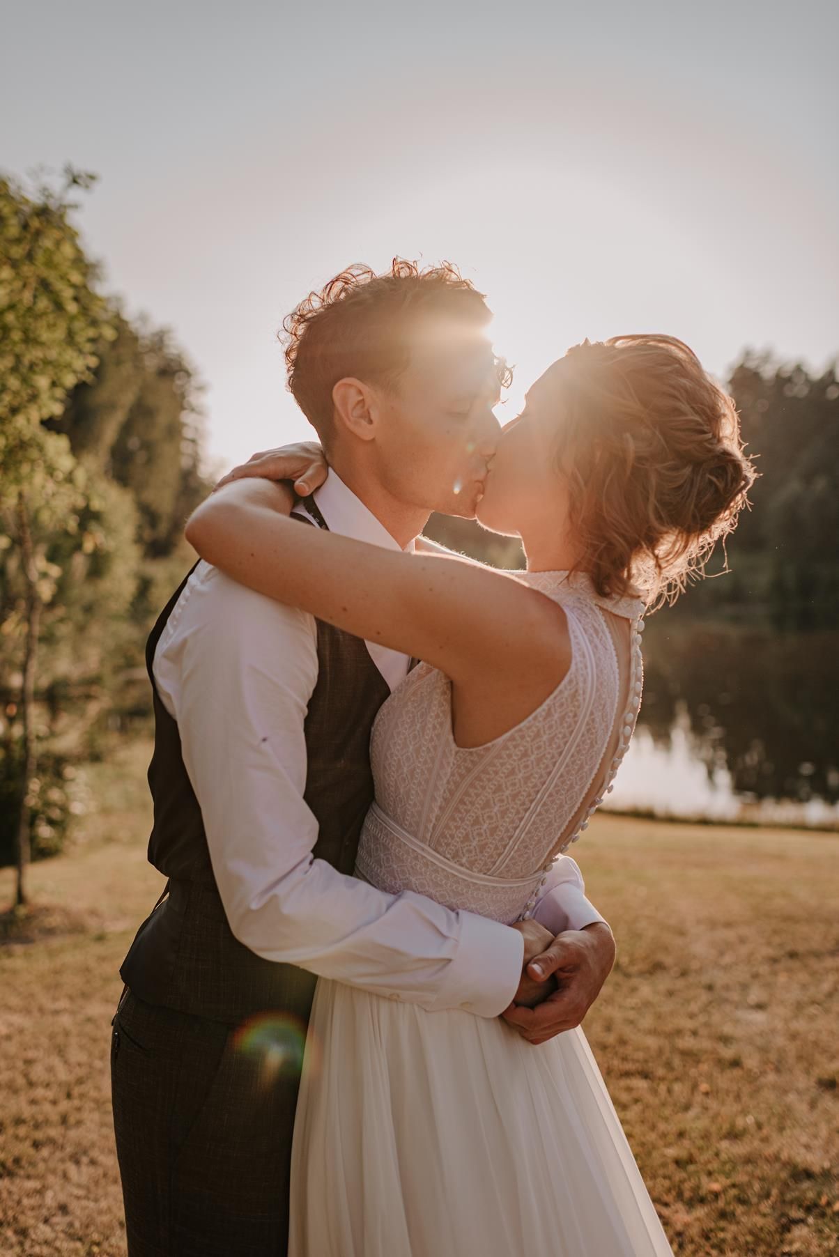 A romantic sunset embrace between newlyweds in a garden setting.