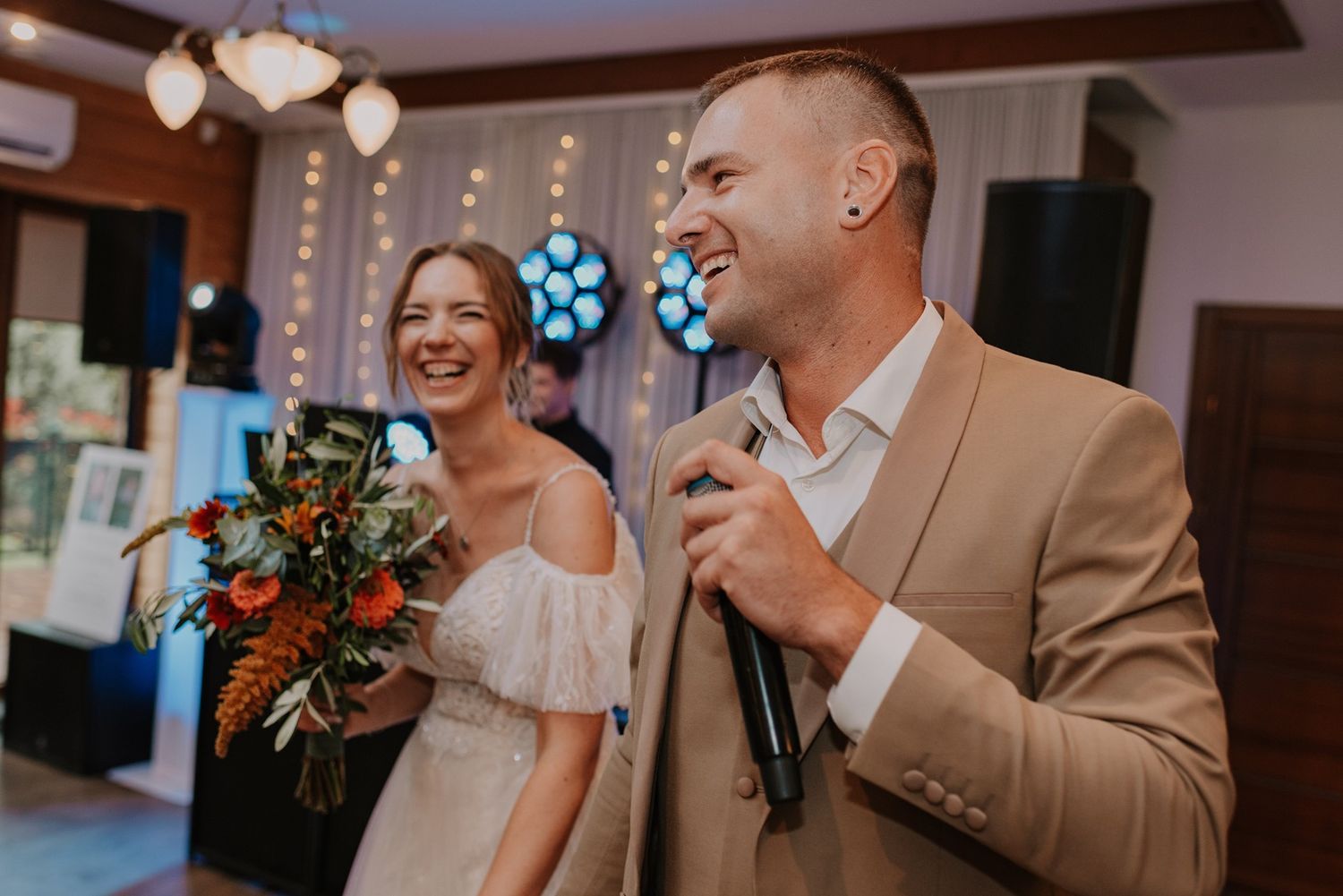 Couple celebrates joyfully during their indoor wedding reception.