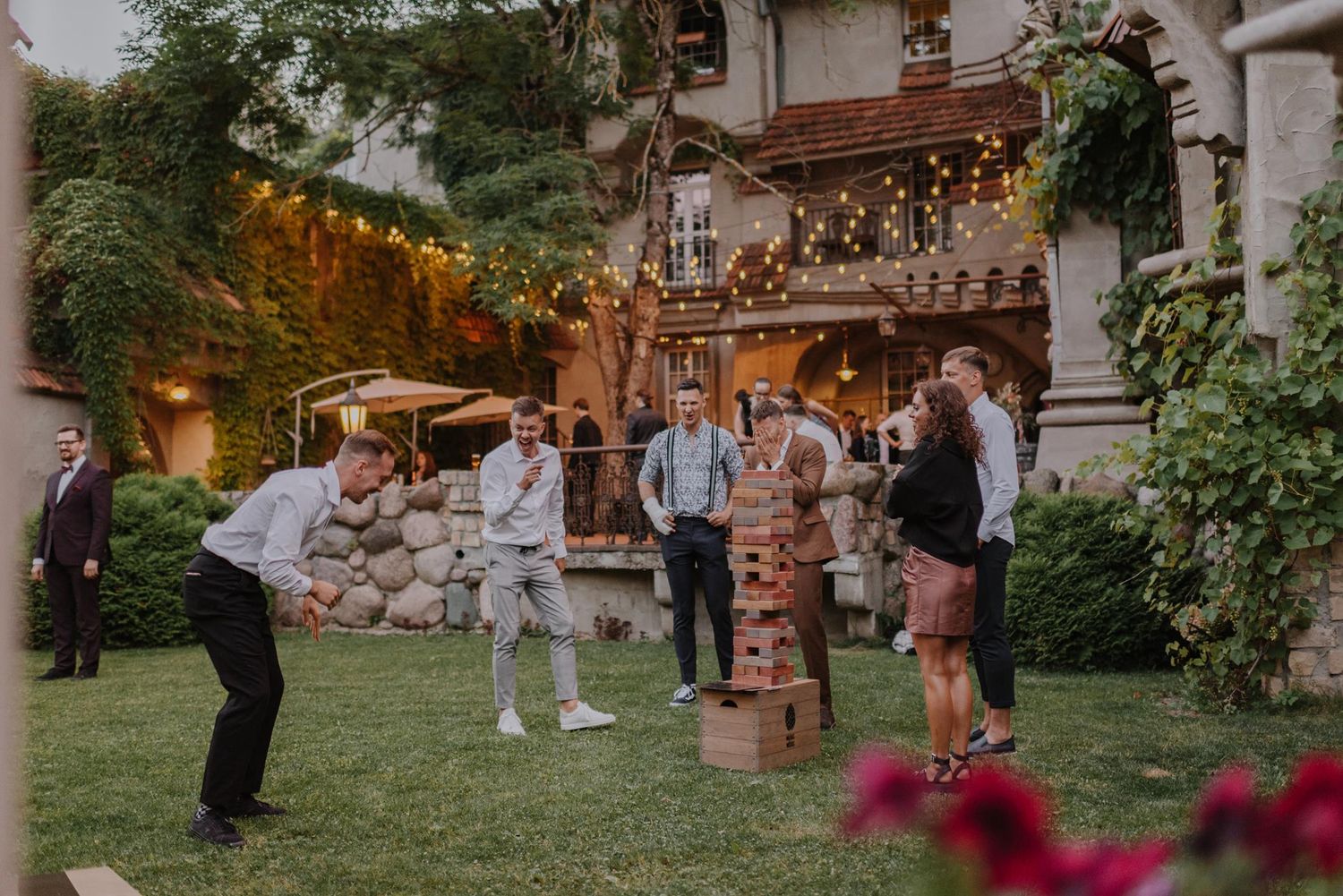 Outdoor wedding reception venue with pillars, string lights and colorful floral arrangements.
