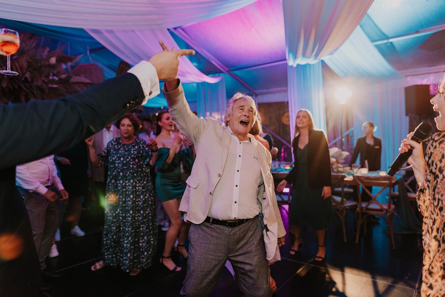 Guests dancing under colorful lighting at evening wedding reception.