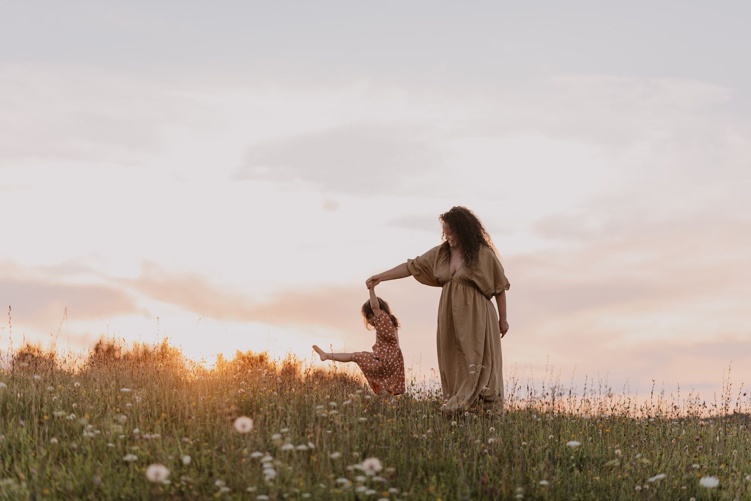 Dreamy sunset scene in wildflower meadow with flowing dress movement.