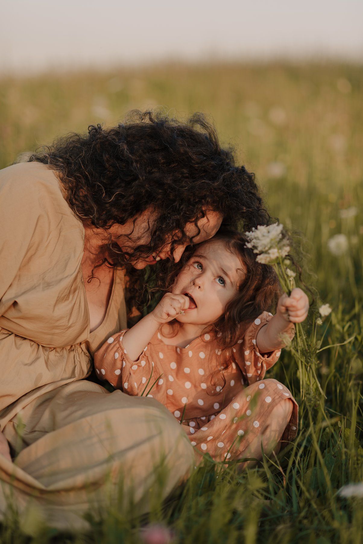 Intimate candid moment captured between two people laughing in a summer field.