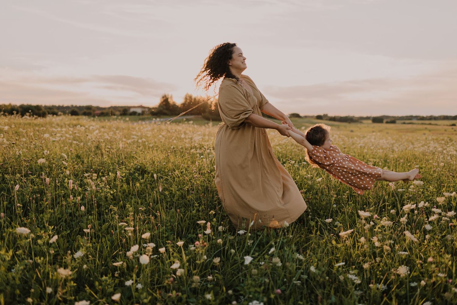 Playful spinning dance captured in a flowering meadow at sunset.