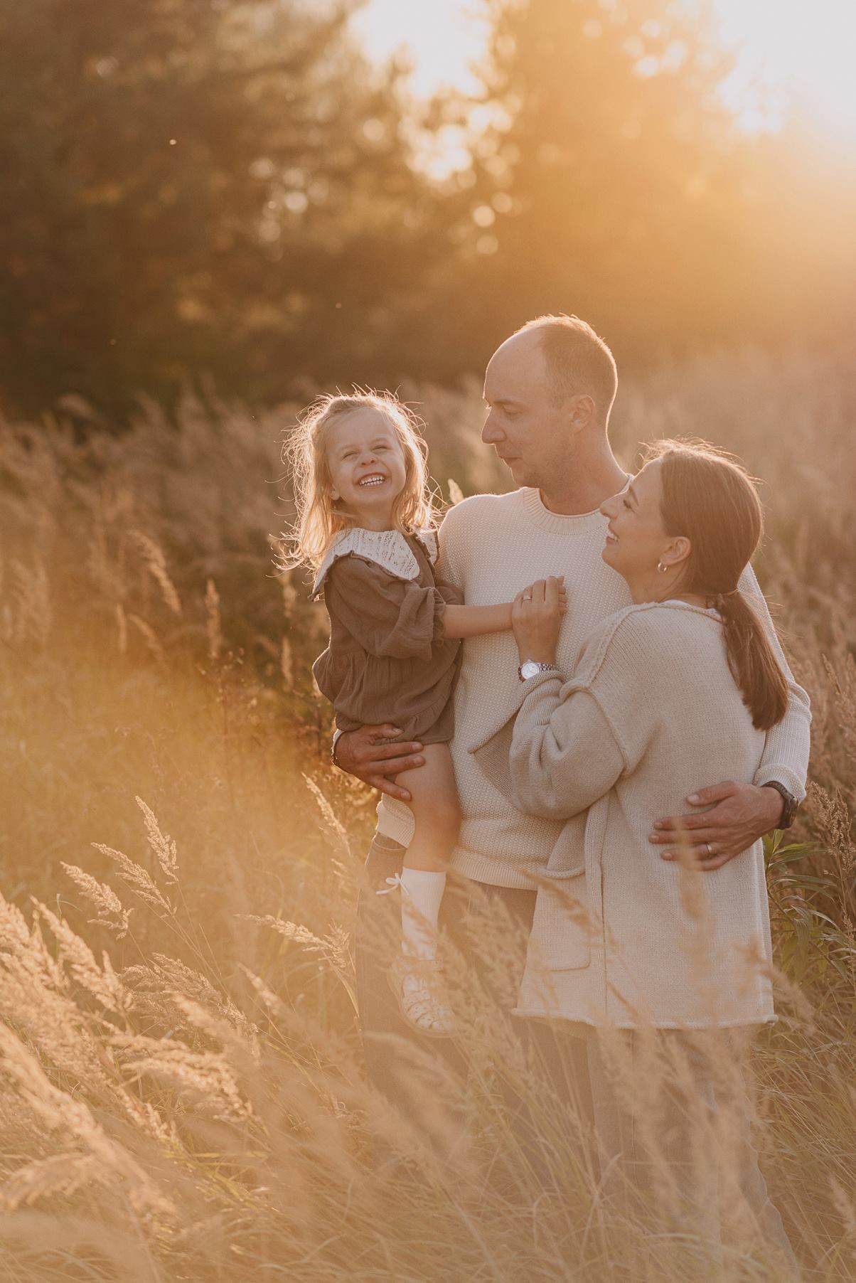 Loving family moment photographed in golden wheat field at sunset.