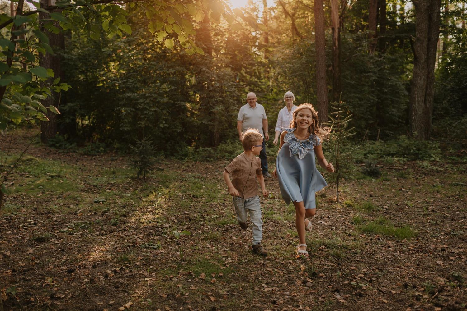 Candid family moment captured in a wooded area during golden hour.