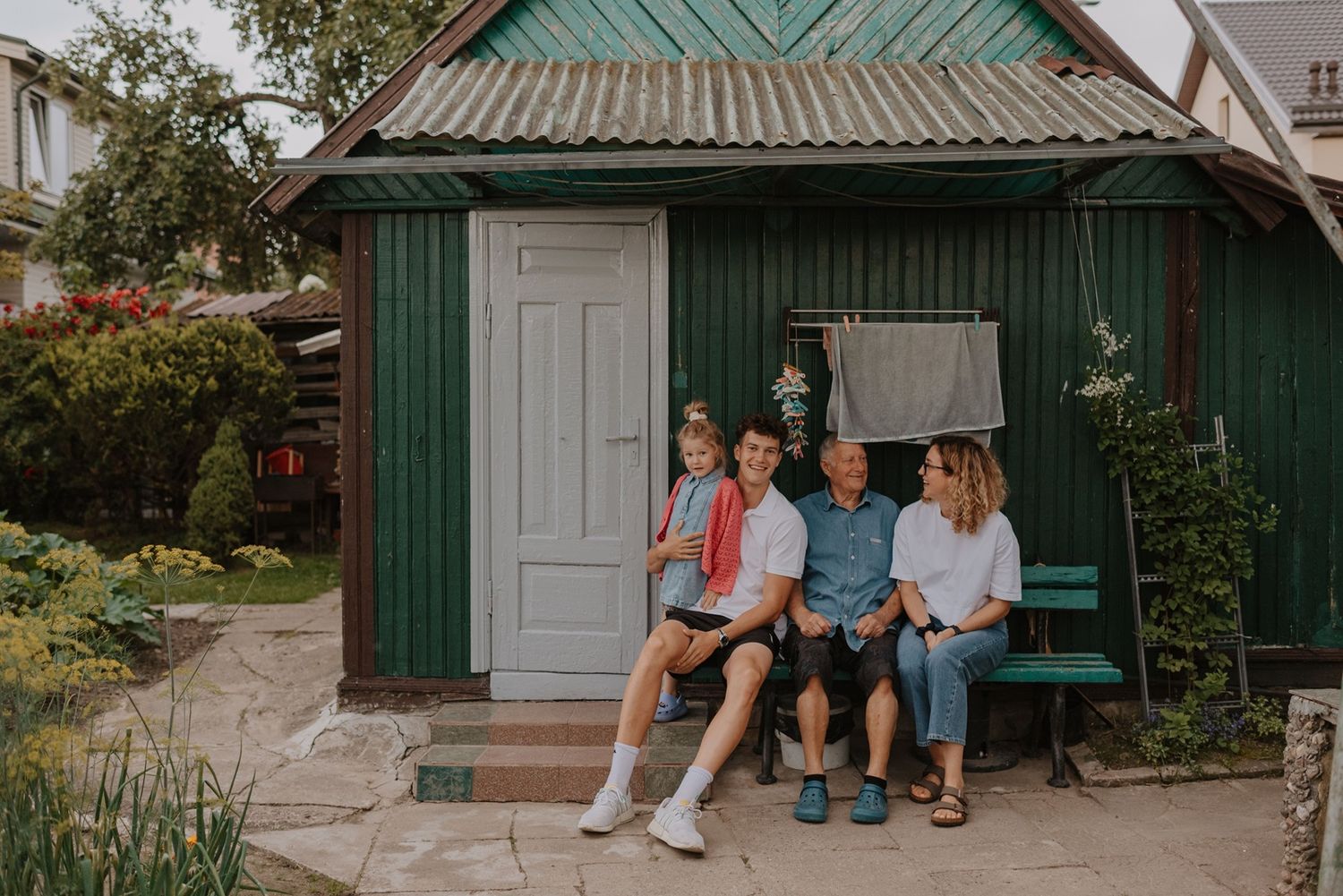 Family gathered on the steps of a green-trimmed cottage for a casual portrait.