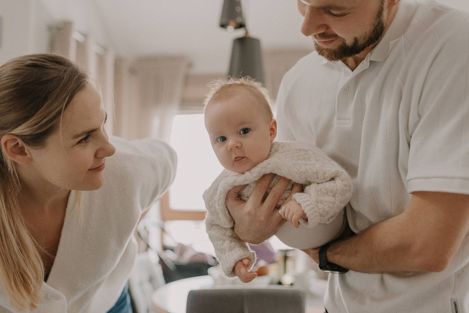 Parents sharing tender moment with infant in bright home setting.