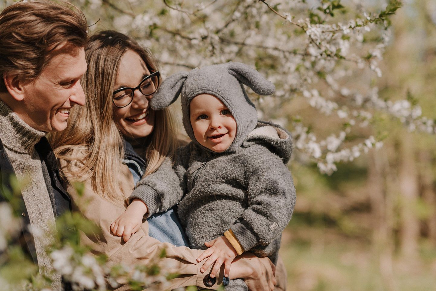Loving family embrace under blooming cherry trees in springtime.
