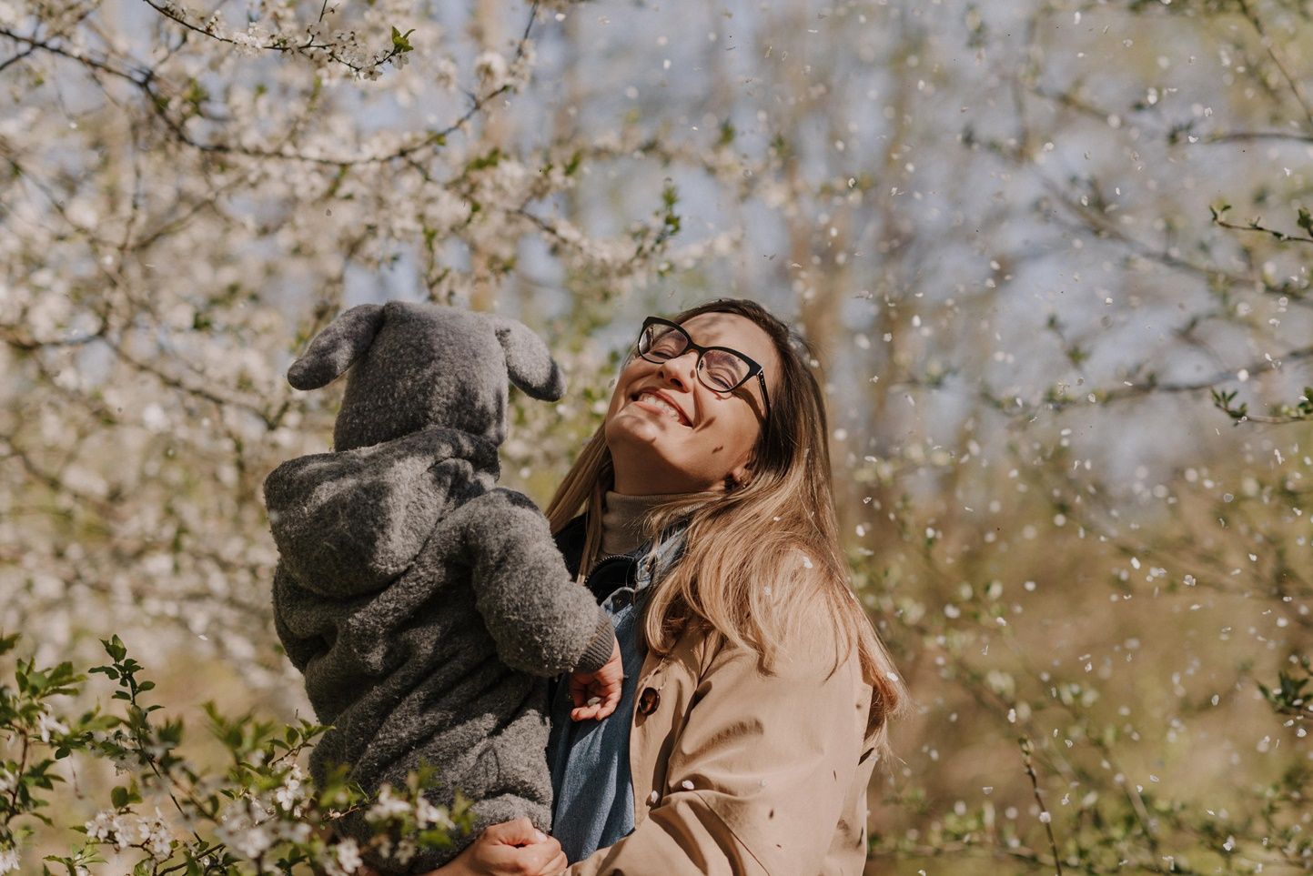 Happy family moment captured beneath flowering spring branches.