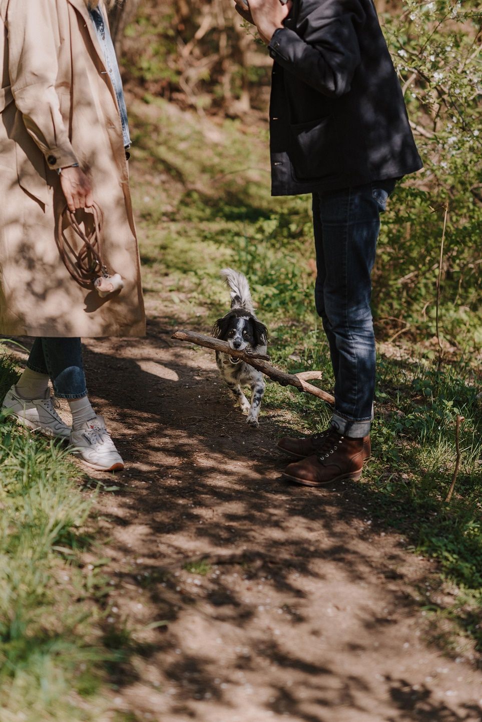 Close-up view of feet walking along a dirt path with a dog in a peaceful forest setting.