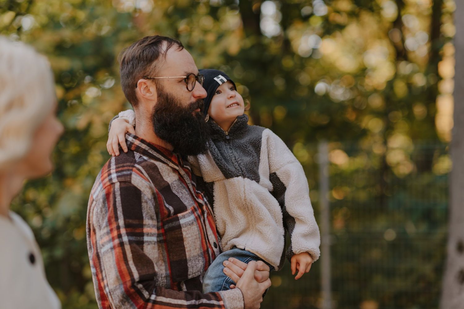 Candid outdoor photo of couple in casual clothing embracing in golden autumn sunlight.