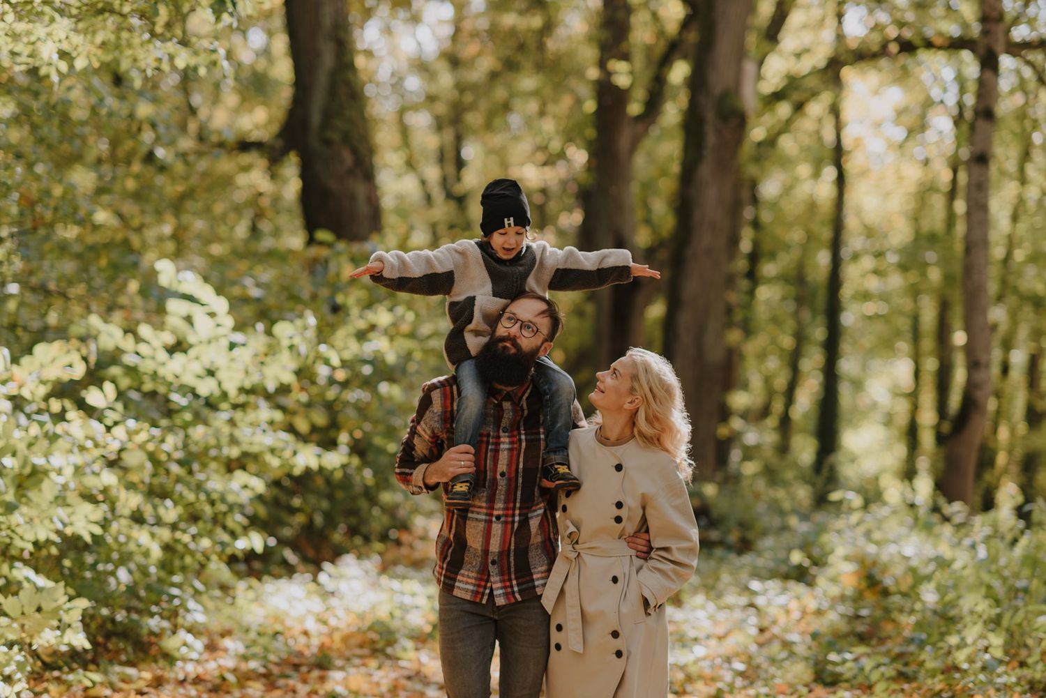 Romantic autumn forest scene with couple in plaid and neutral tones among trees.