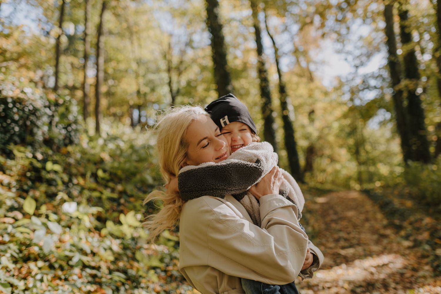 Intimate moment captured between couple on wooded trail during golden hour.