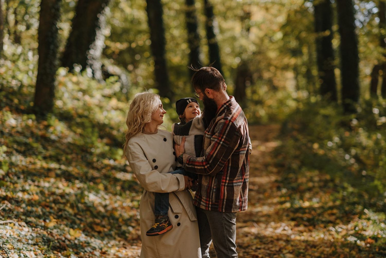 Natural autumn scene with couple sharing tender moment on leaf-covered forest trail.