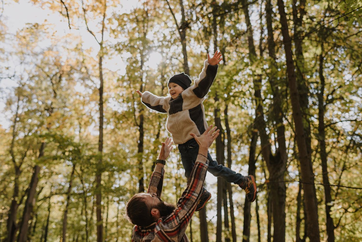 Carefree moments captured between two people in a sunlit autumn forest.