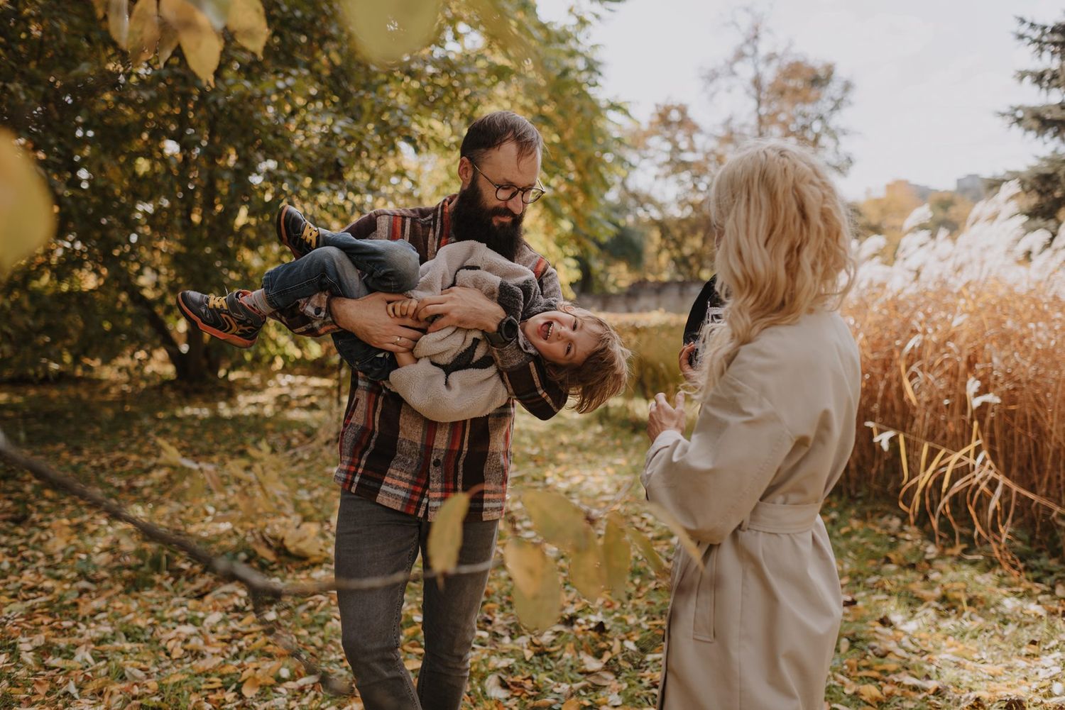 A playful autumn photoshoot showing fun interactions in a golden-lit forest setting.
