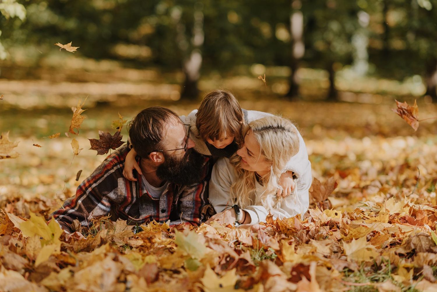People enjoying playtime in a carpet of fallen autumn leaves.