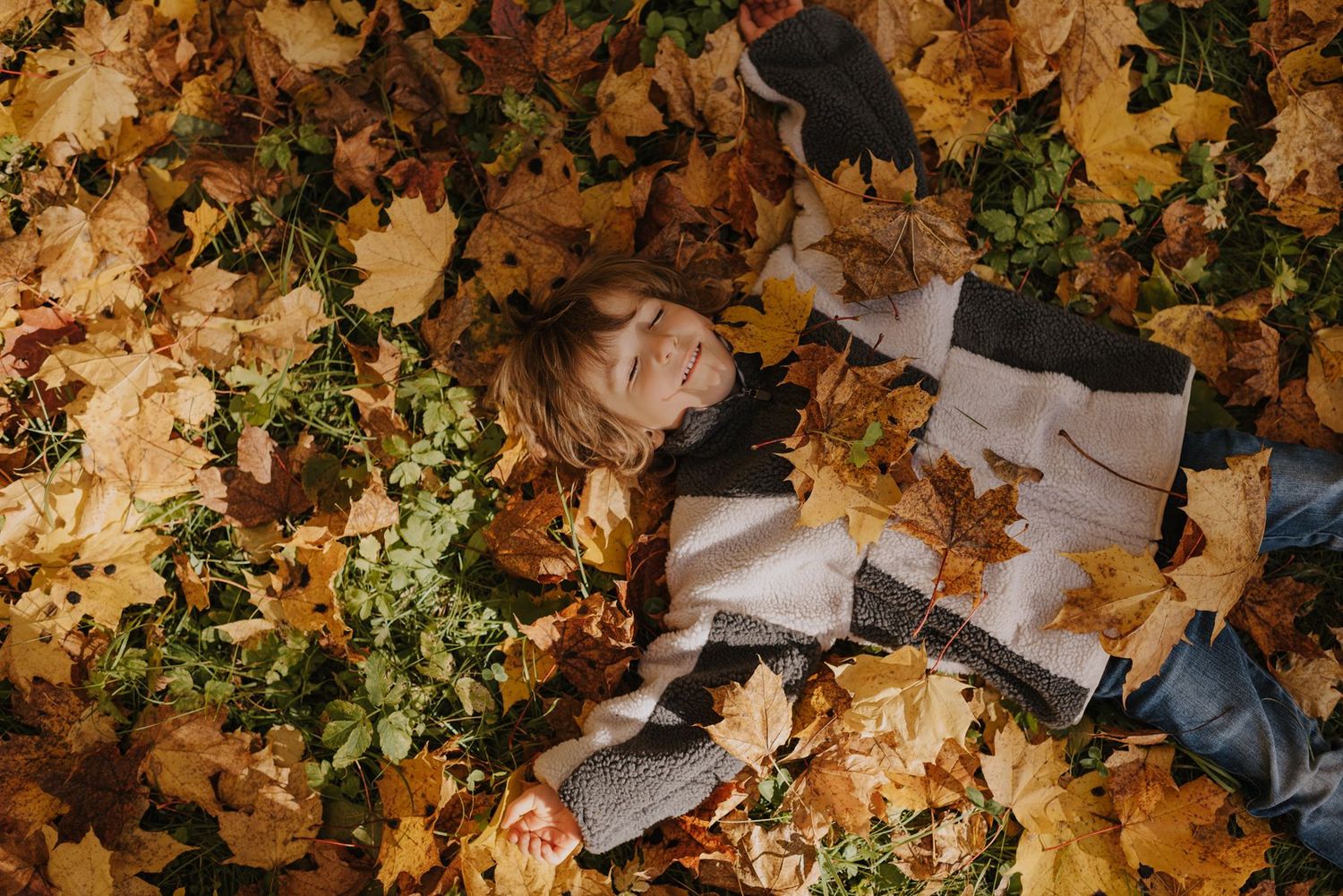Candid moments captured while playing in golden autumn leaves.