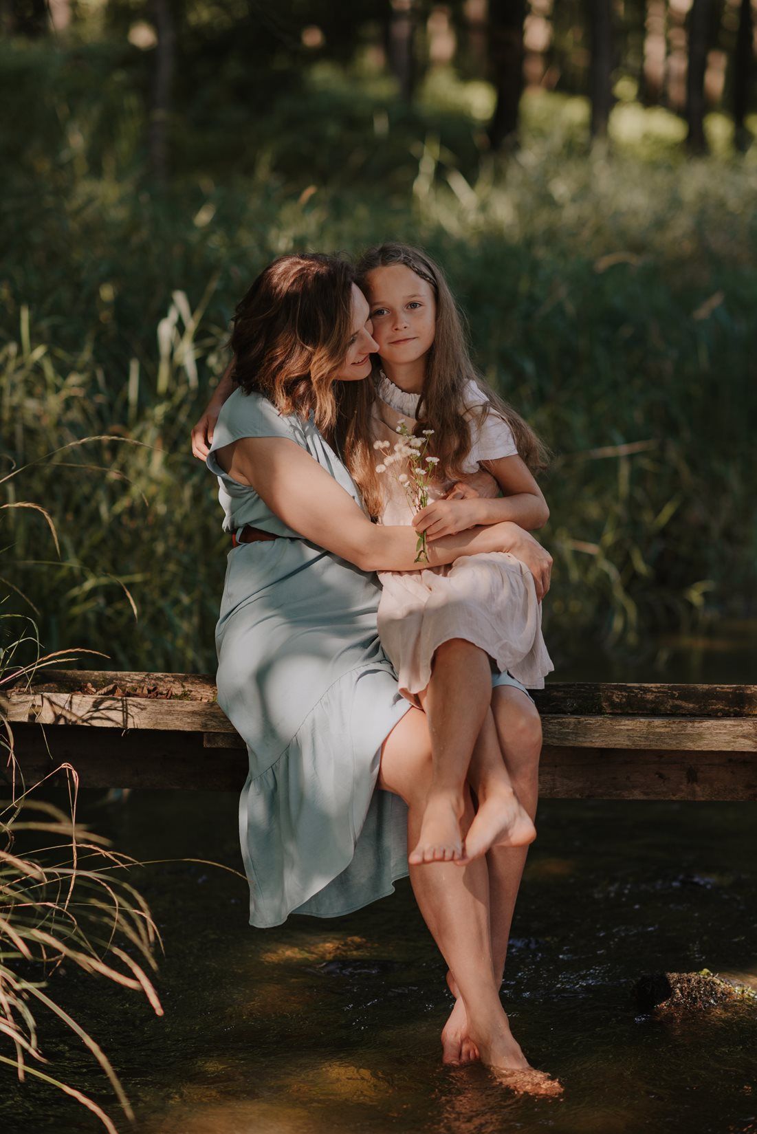 Intimate family moment captured on a wooden bench in golden evening light.