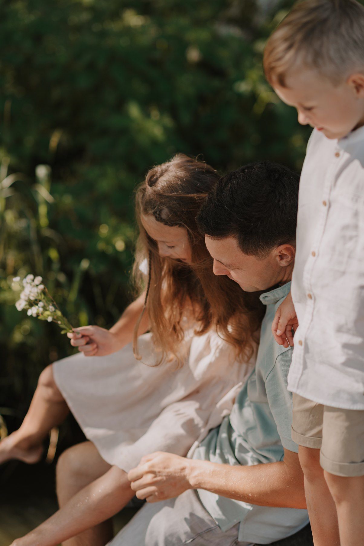 Family gathering close together for an intimate outdoor portrait in warm sunlight.