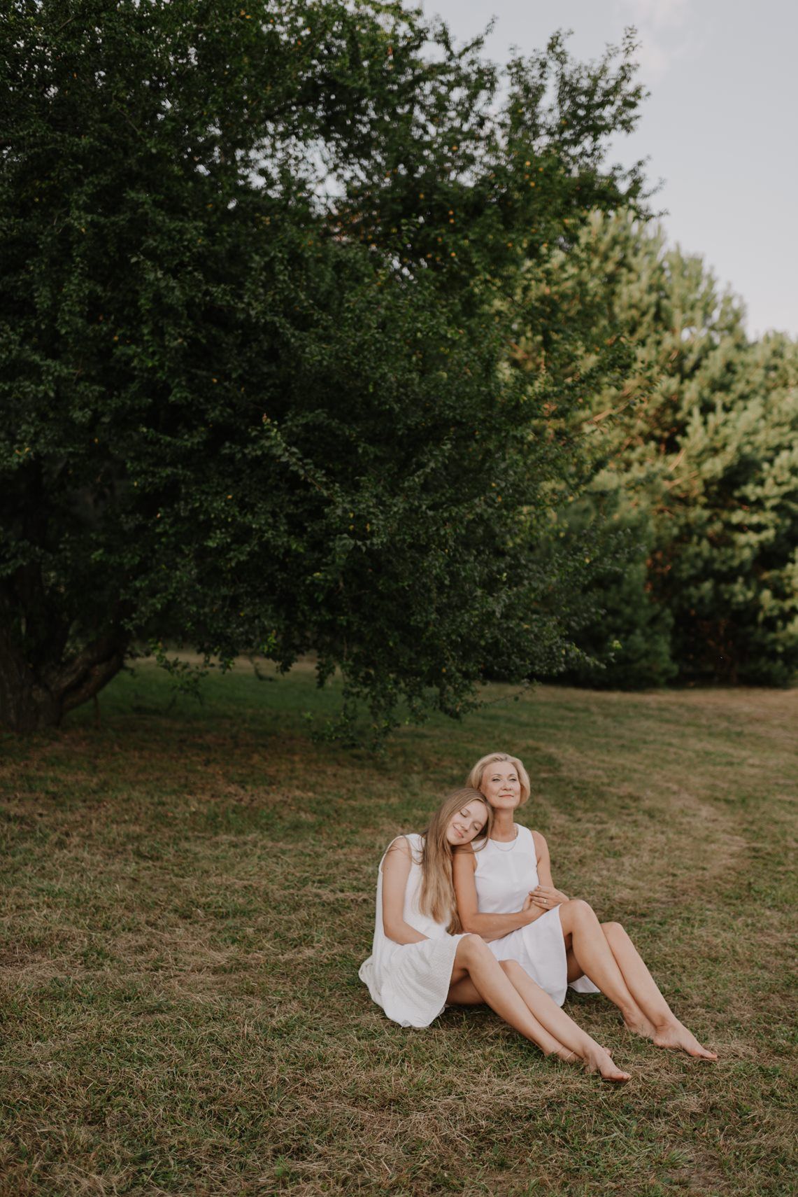 Friends relaxing on a grassy hillside during a summer outdoor photoshoot.
