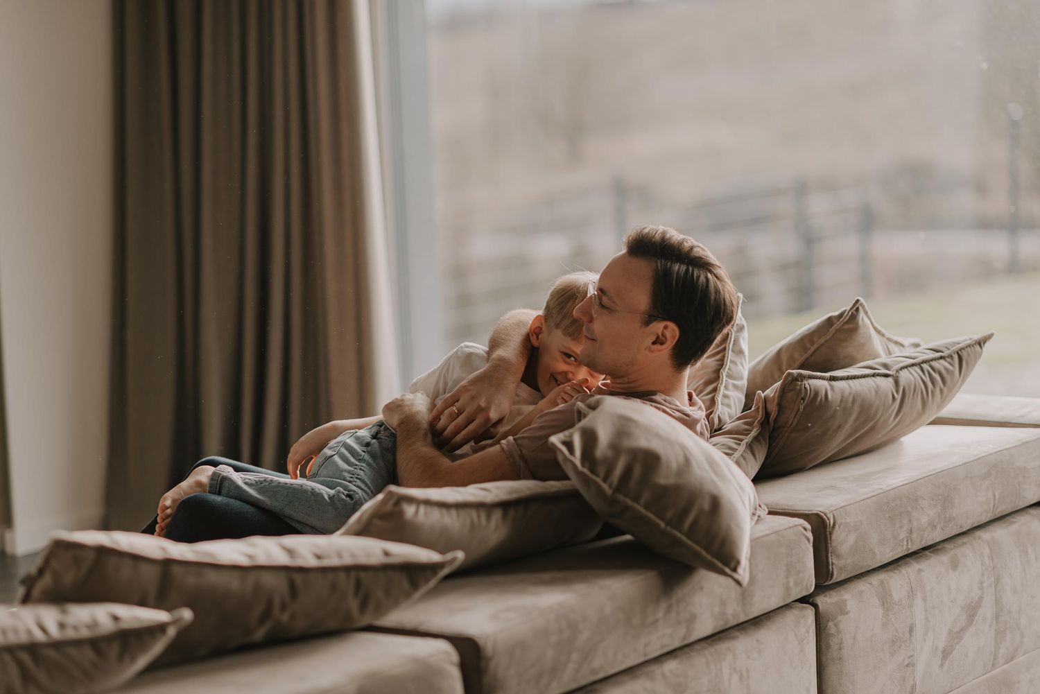 Tender family moment shared on a comfortable couch by a window.