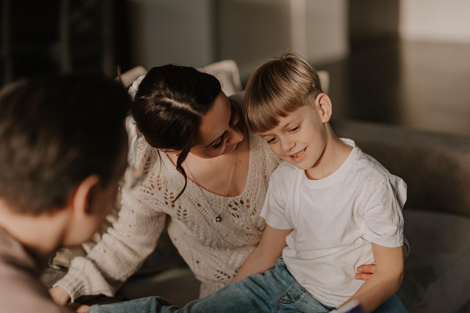 Intimate family moment captured in warm, muted tones on a sofa.