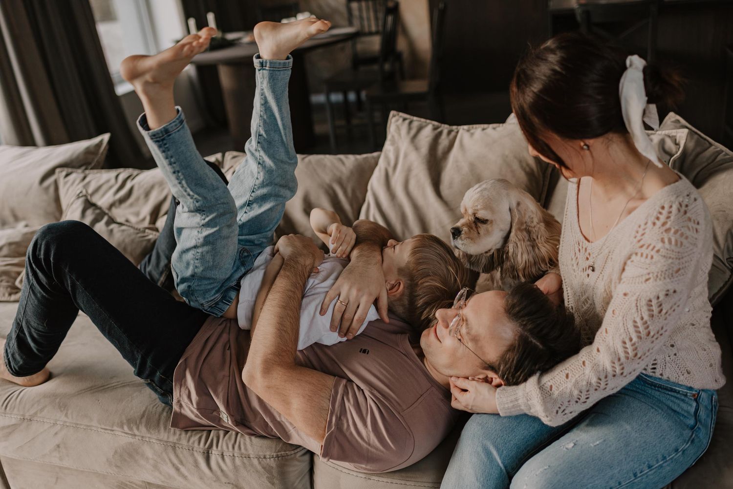 Playful family interaction on a comfortable couch in a living room setting.