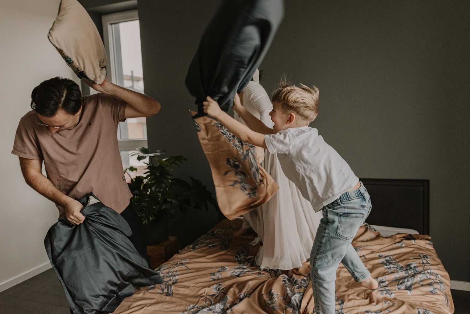 Energetic family playtime with everyone jumping and laughing on bed.