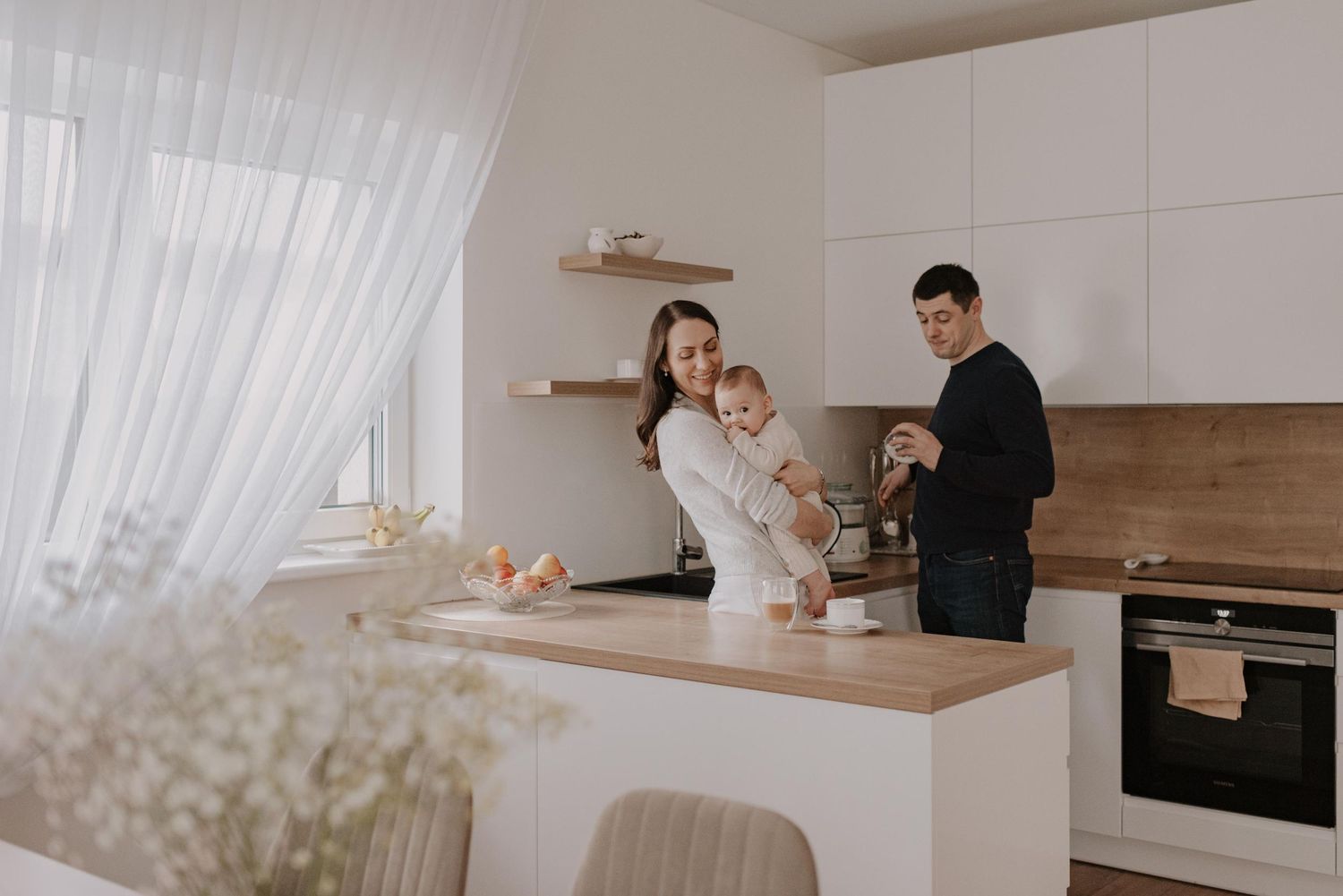 Modern white kitchen interior with family members in casual setting.
