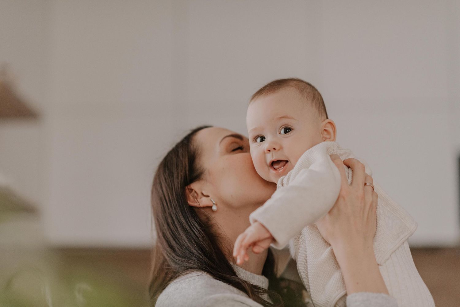 Intimate indoor portrait of parent feeding baby in soft natural lighting.