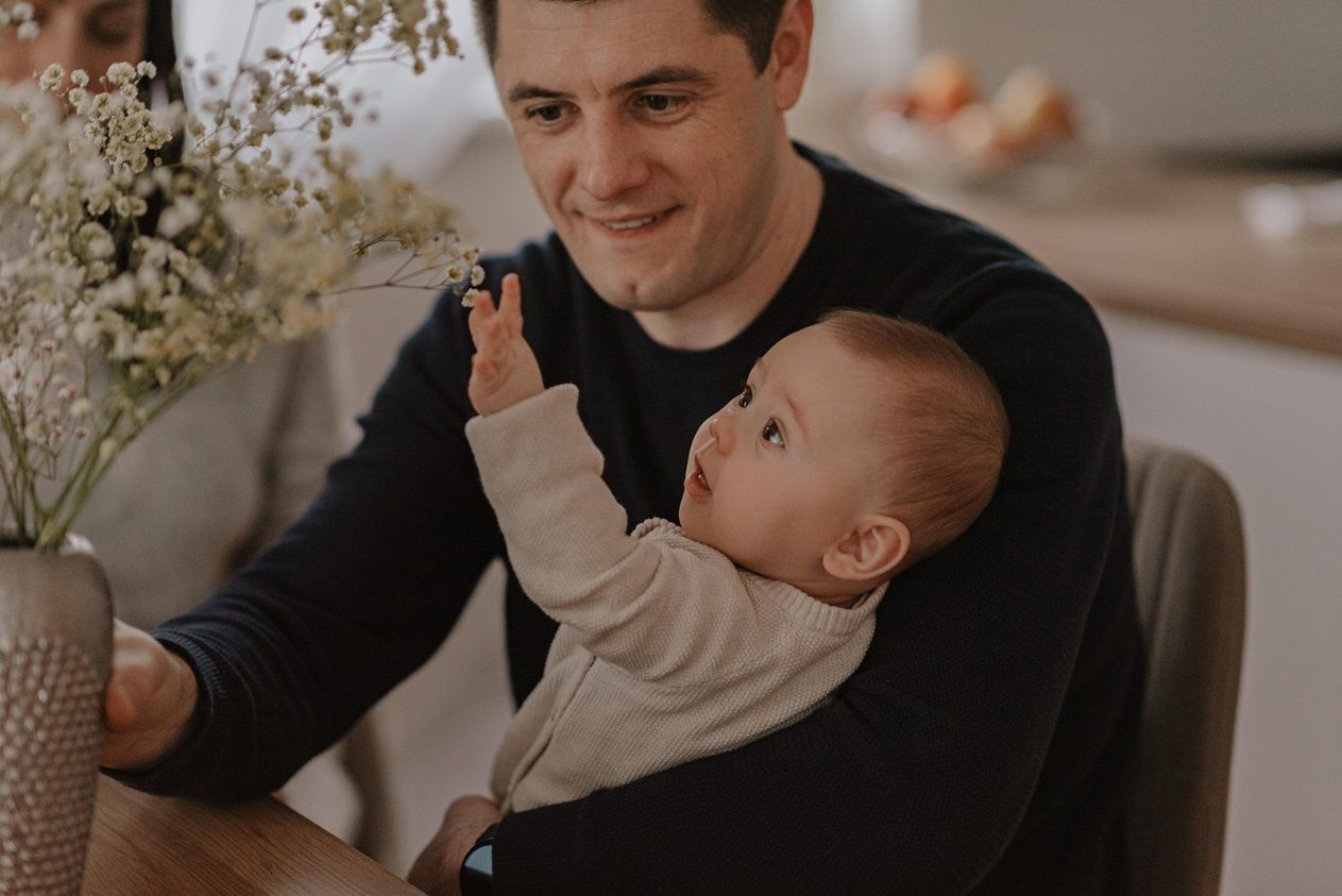 Parents share joyful moments with infant during mealtime at home.